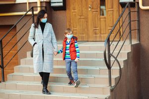 Mother and young boy descend stairs with masks on